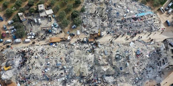 This aerial view shows residents searching for victims and survivors amid the rubble of collapsed buildings following an earthquake that struck a Basniyah village near the town of Harem in Syria's northwestern rebel-held Idlib province on the border with Turkey, on February 6, 2022. 