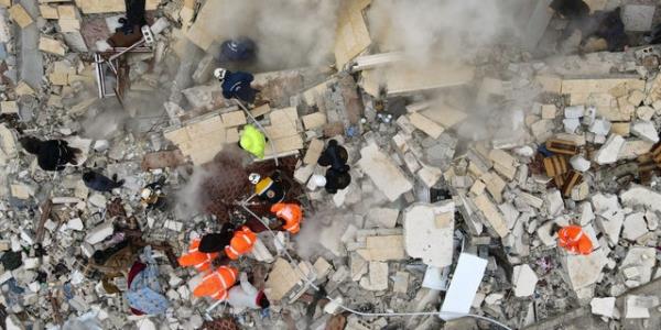 This aerial view shows residents, with the help of bulldozers, searching for victims and survivors under the rubble of collapsed buildings, following the earthquake that struck the town of Sarmada in the countryside of Idlib Governorate, northwestern Syria, early on February 6, 2023. 